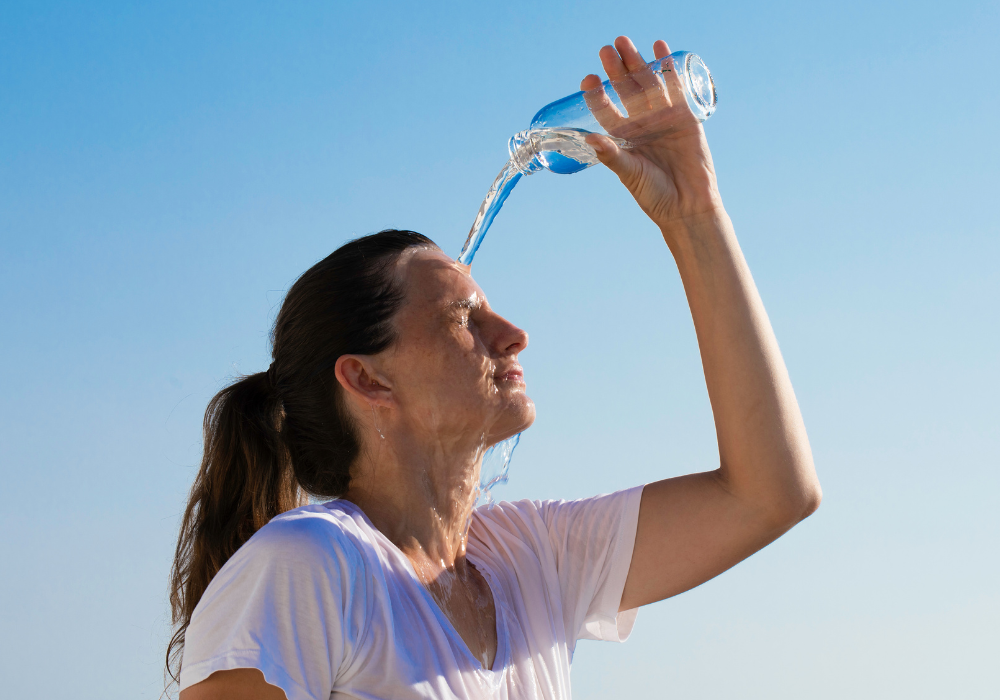 Mulher se Hidratando por causa das fortes ondas de calor mulher jogando água no rosto por causa do intenso calor